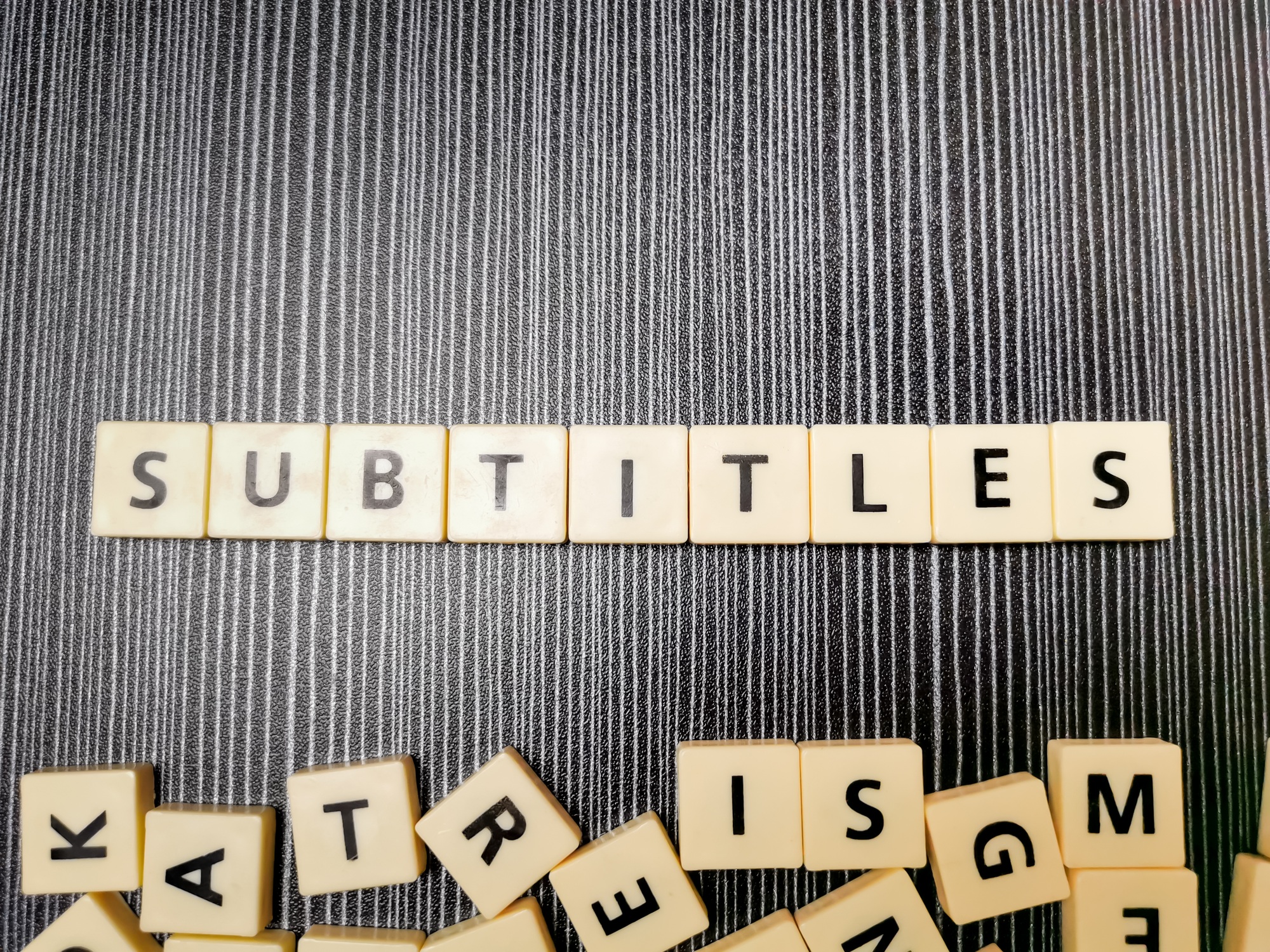 Word subtitles made from square letter tiles against black background.