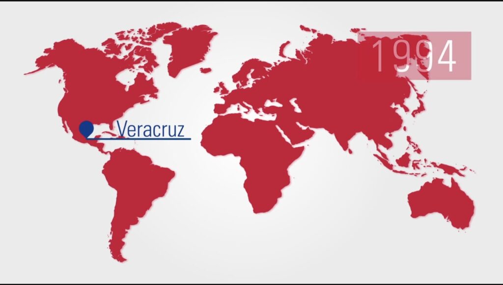 Mapa mundial con marcador en Veracruz y año 1994, representando el origen de una empresa industrial global.