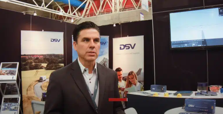 Ejecutivo de DSV en stand de feria comercial, grabando video corporativo para destacar presencia en exposiciones logísticas y de transporte.
