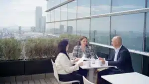 Reunión ejecutiva entre profesionales en terraza corporativa durante grabación de video corporativo para empresa.