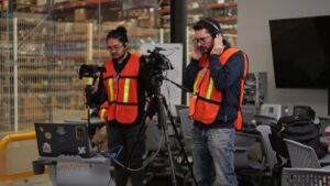 Equipo de producción de video corporativo grabando dentro de una planta industrial con cámaras profesionales y personal usando equipo de seguridad.