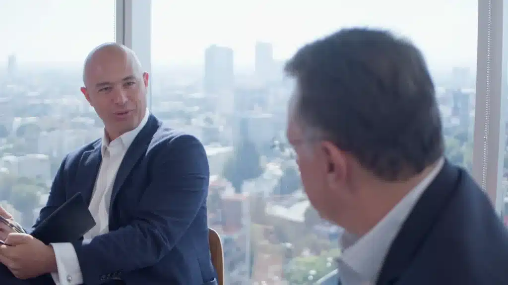 Conversación entre dos profesionales en oficina con vista urbana