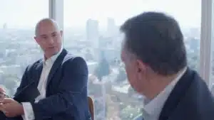 Conversación entre dos profesionales en oficina con vista urbana