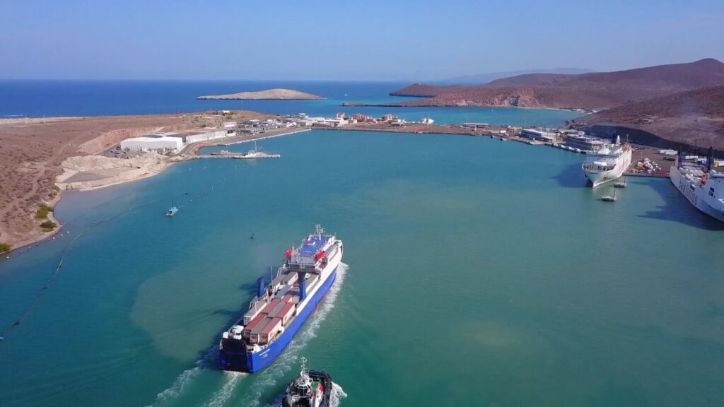 Vista aérea de puerto industrial con embarcaciones de carga en operación