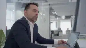 Profesional trabajando en computadora portátil dentro de oficina corporativa