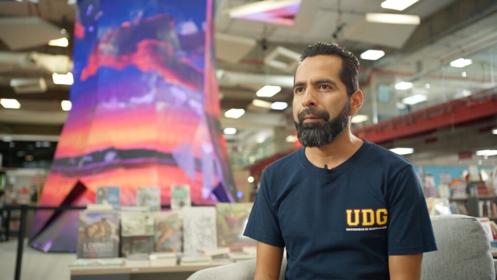 Persona entrevistada en espacio educativo con material bibliográfico al fondo