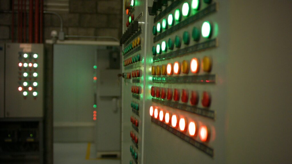 Tablero de control industrial con indicadores luminosos verdes, ámbar y rojos en el área de servicios de una planta.