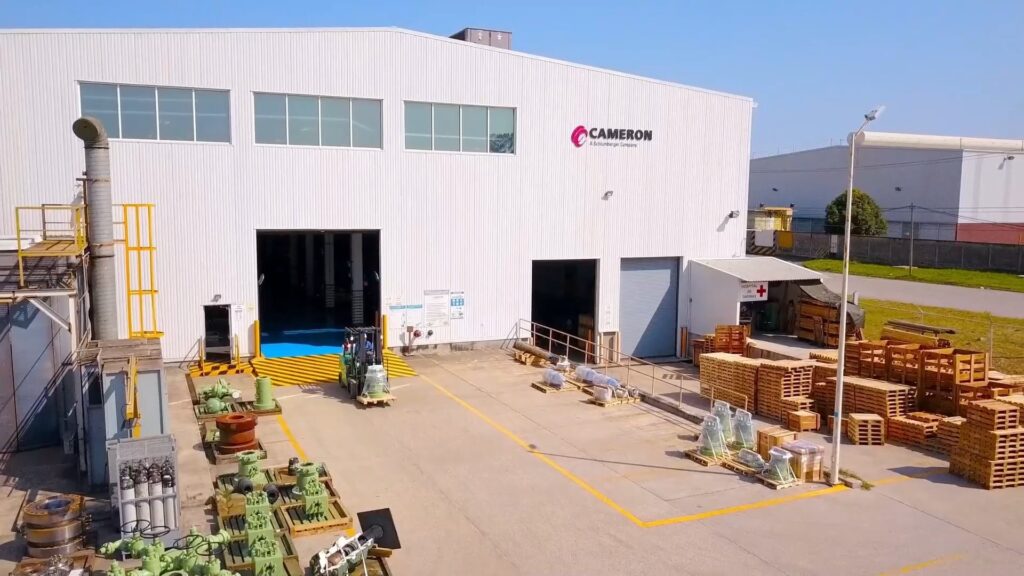 Vista elevada del exterior de una planta de manufactura con montacargas en operación, tarimas y componentes industriales en el patio de maniobras.