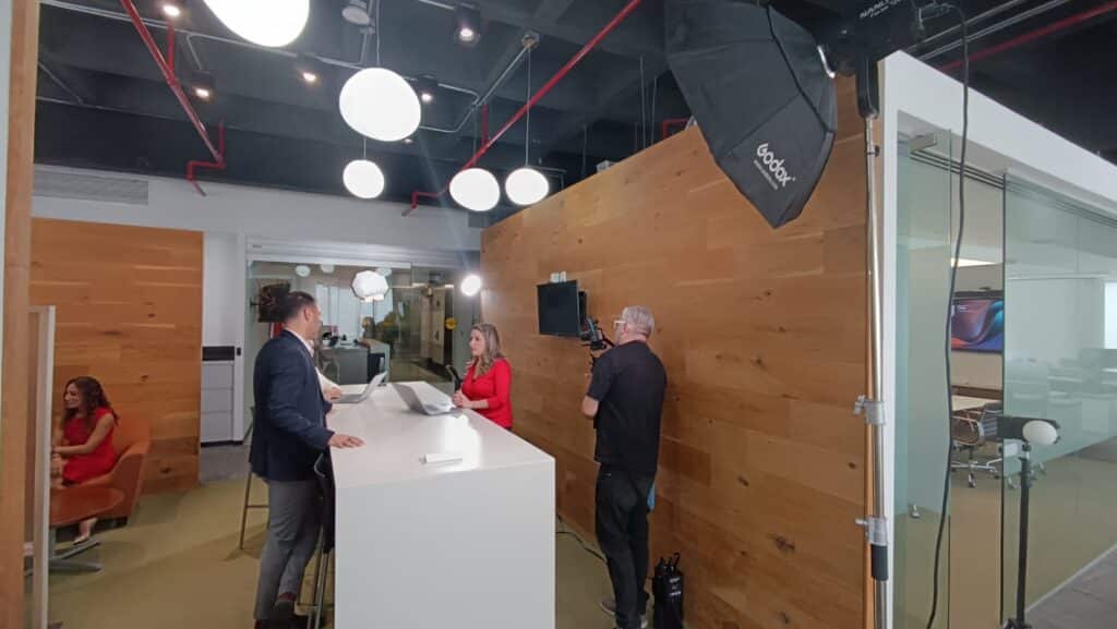 Equipo de f-visual grabando una entrevista corporativa en oficina, con cámara, softbox y luz continua montada.